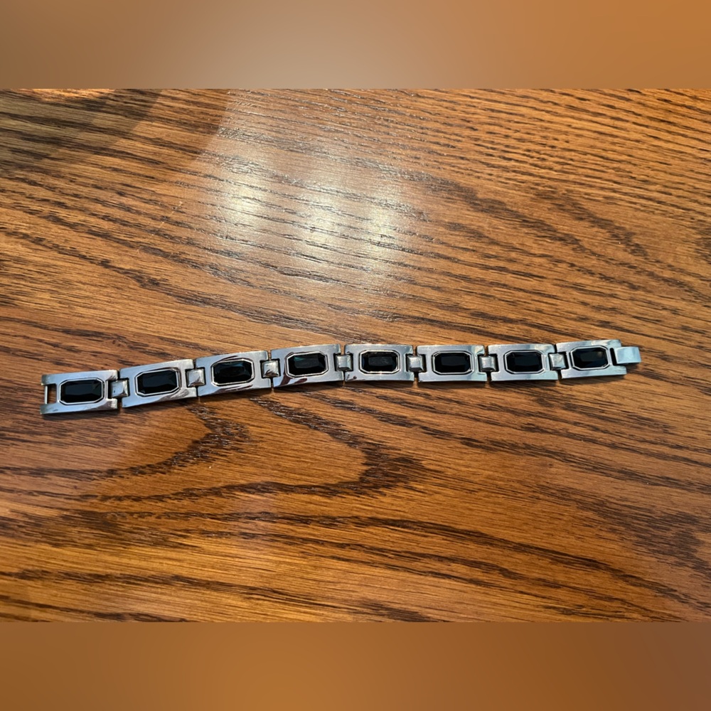 Silver tone metal bracelet with black accents. marked “BGE”